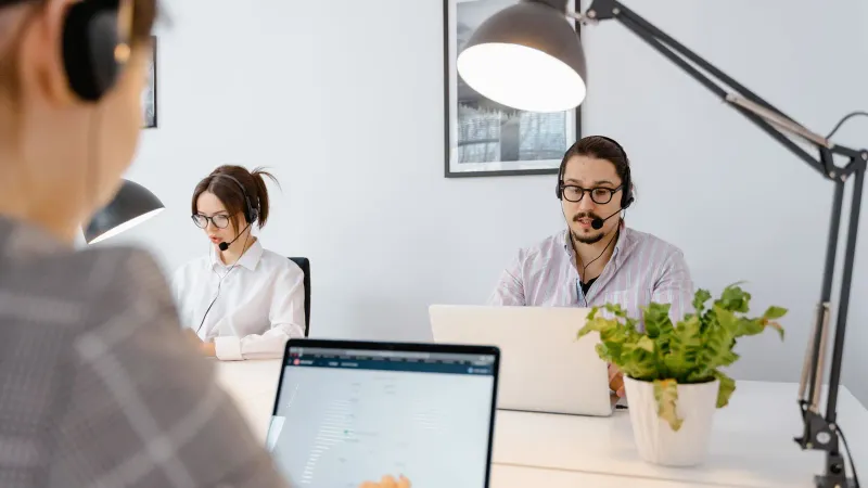 Professionelle Callcenter-Agenten, die in einem hellen modernen Büro an Laptops arbeiten.